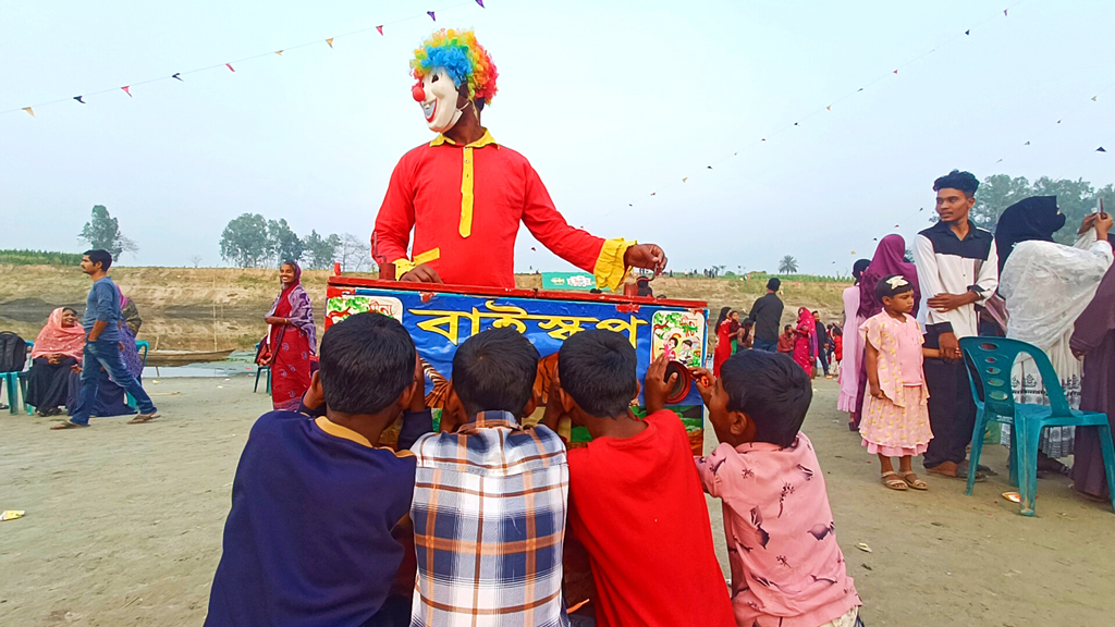 মানিকগঞ্জের ঘিওরে কালীগঙ্গা নদীর পাড়ে পার্বণ নবান্ন উৎসব ও গ্রামীণ মেলায় হারিয়ে যাওয়া ঐতিহ্য বায়োস্কোপে মুগ্ধ শিশু-কিশোর। কাঠের বাক্সে চোখ লাগিয়ে সুরের তালে ছবি দেখতে বেশ ভিড় করছে তারা। বায়োস্কোপে প্রাণী, নায়ক-নায়িকা, খেলোয়াড়, ঝরনা, পাহাড়, দর্শনীয় স্থানসহ অনেক ধরনের স্থিরচিত্র একের পর এক দেখানো হয়। ছবি: মো. আব্দুর রাজ্জাক