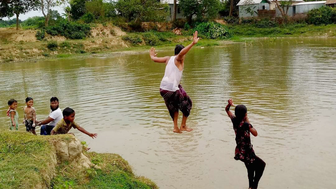 ভ্যাপসা গরমে পুকুরে গোসলে নেমেছে শিশুরা। আনন্দে লাফিয়ে পড়ছে পুকুরে। তিতাস, কুমিল্লা, ১৩ মে ২০২৩। ছবি: মো. কবির হোসেন।