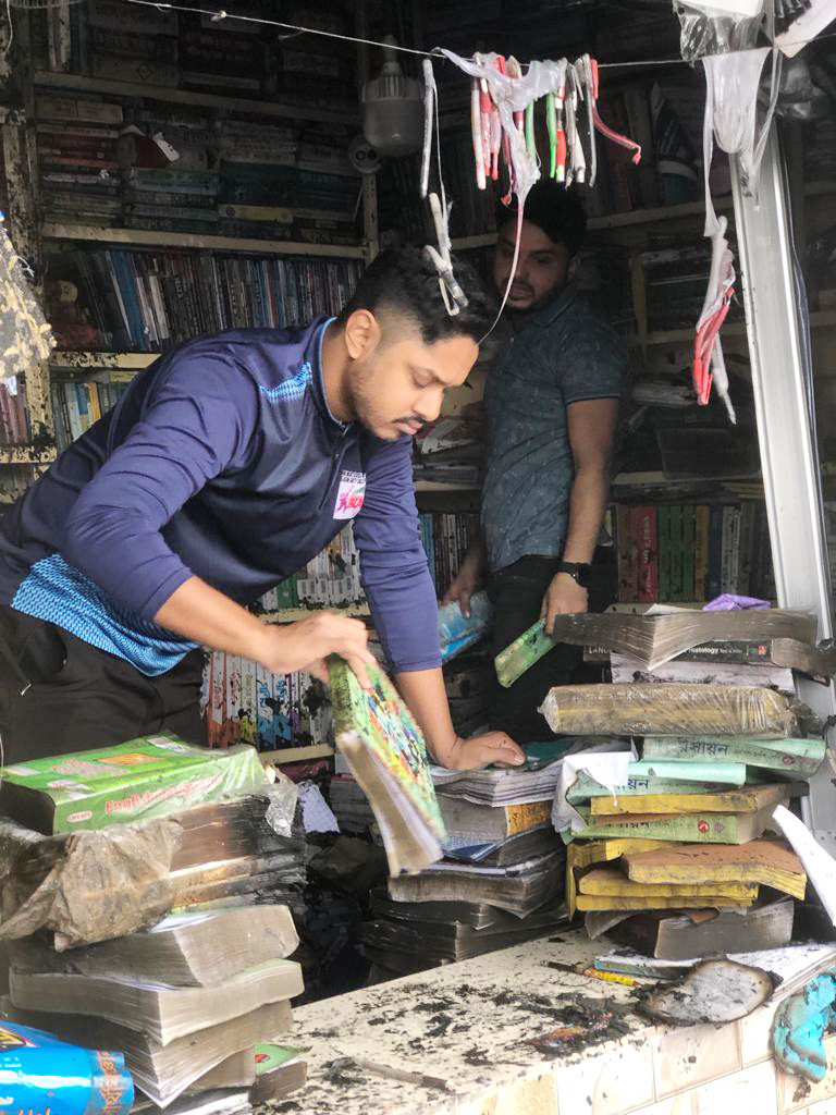 ক্ষতিগ্রস্ত দোকানগুলো থেকে ভেজা-আধা ভেজা অক্ষত বইগুলো বের করে নিচ্ছেন এক দোকানি