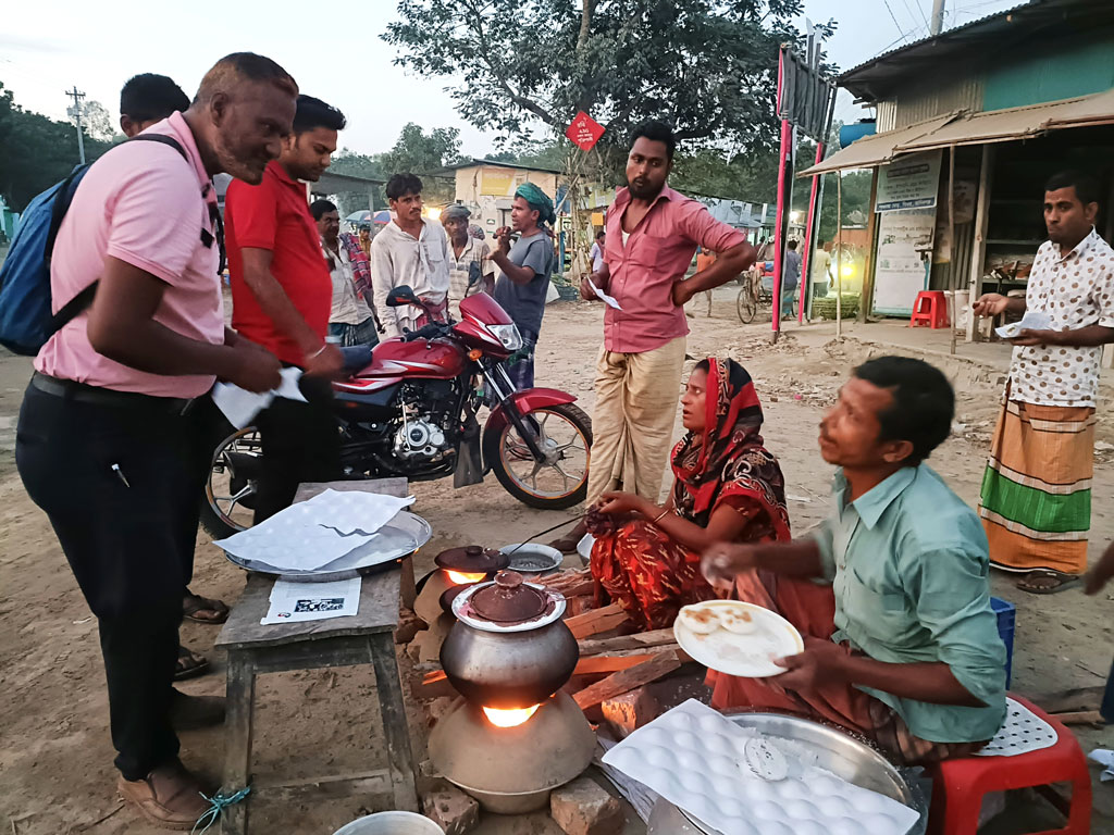 হেমন্তে হালকা কুয়াশাচ্ছন্ন সকালে ধোঁয়া ওঠা ভাপা ও চিতই পিঠা খেতে অস্থায়ী এক পিঠার দোকানে ভিড় জমেছে মানুষের। খেজুর গুড় আর নতুন চালের গুঁড়া দিয়ে তৈরি হয় এসব পিঠা। ঘিওরে পঞ্চ রাস্তা মোড়ে বসে বেশ কয়েকটি অস্থায়ী পিঠার দোকান। ঘিওর, মানিকগঞ্জ, ২ নভেম্বর ২০২৩। ছবি: আব্দুর রাজ্জাক