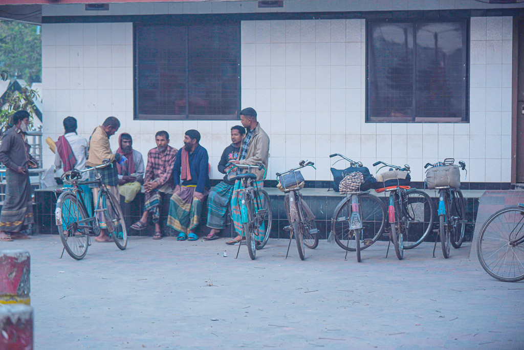 তাঁরা কুলির কাজ করেন। প্রতিদিন সকালে কাকডাকা ভোরে বাইসাইকেলে বিভিন্ন উপজেলা থেকে এসে জড়ো হন কুড়িগ্রাম শহরের কেন্দ্রীয় কবরস্থানের সামনে। ঢাকা থেকে ছেড়ে আসা বিভিন্ন মালবাহী গাড়িগুলো শহরে ঢুকলেই ডাক পরে তাঁদের। এখনো কোনো মালবাহী গাড়ি শহরে না ঢোকায় সবাই মিলে মেতেছেন খোশগল্পে। কুড়িগ্রাম, রংপুর। ১৩ মার্চ, ২০২৩। ছবি: আব্দুর রহিম পায়েল