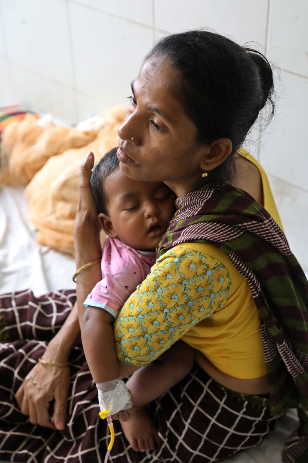 ডেঙ্গু জ্বর নিয়ে গত পরশু রাজধানীর মুগদা মেডিকেল কলেজ হাসপাতালে ভর্তি করানো হয় এই শিশুকে। প্লাটিলেটের পরিমাণ কমে যাওয়ার রিপোর্ট পেয়ে উদ্বিগ্ন হয়ে পড়েন মা। চোখে-মুখে চিন্তার ছাপ নিয়ে ঘুমন্ত সন্তানকে বুকে জড়িয়ে ধরেন। ছবি: আজকের পত্রিকা