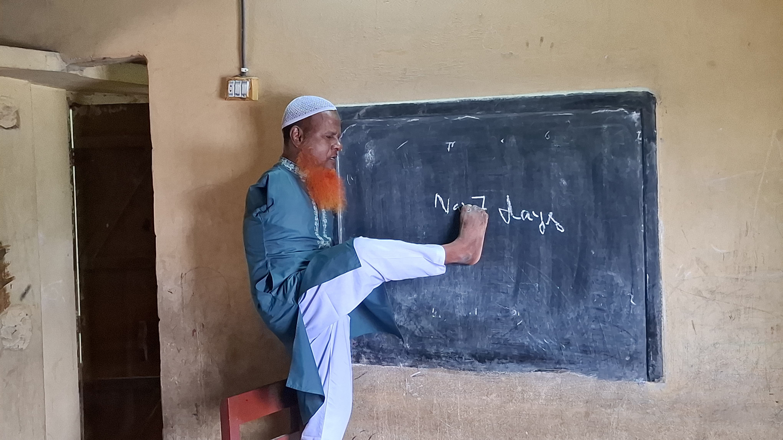 দুই হাত নেই, তবু পা দিয়ে লিখে আলো ছড়াচ্ছেন নরসিংদীর ‘দুখু মিয়া’