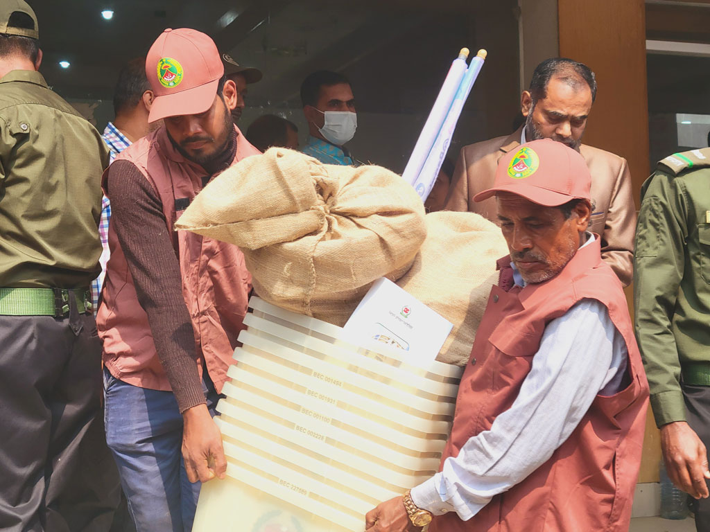 ভোট শুরুর আগে বিভিন্ন কেন্দ্রে সরঞ্জামাদি নিয়ে যাচ্ছেন কর্মকর্তারা। নরসিংদীর রায়পুরা হলরুমের সামনে থেকে আজ সকালে তোলা। ছবি: হারুনূর রশিদ