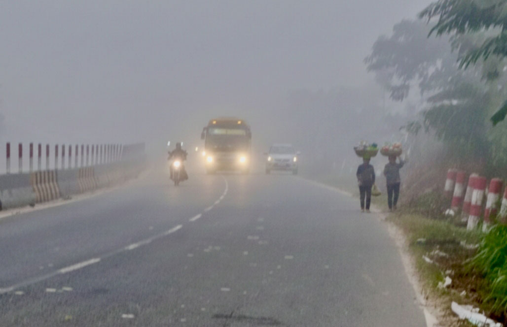 পৌষের ঘন কুয়াশায় ঢাকা পড়েছে মহাসড়ক। হেডলাইট জ্বালিয়ে ধীরগতিতে চলছে বাস, কার ও মোটরসাইকেল। মাথায় ঝুড়ি নিয়ে বাজারের পথে চলছেন শ্রমজীবী মানুষ। আজ সকালে ঢাকা-আরিচা মহাসড়কের মানিকগঞ্জের বানিয়াজুরী বাসস্ট্যান্ড এলাকা থেকে তোলা। ছবি: আব্দুর রাজ্জাক