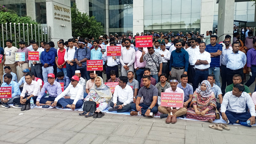 ফটকের সামনে রাস্তায় বসে পড়েছেন এনবিআর কর্মকর্তা-কর্মচারীরা। ছবি: আজকের পত্রিকা
