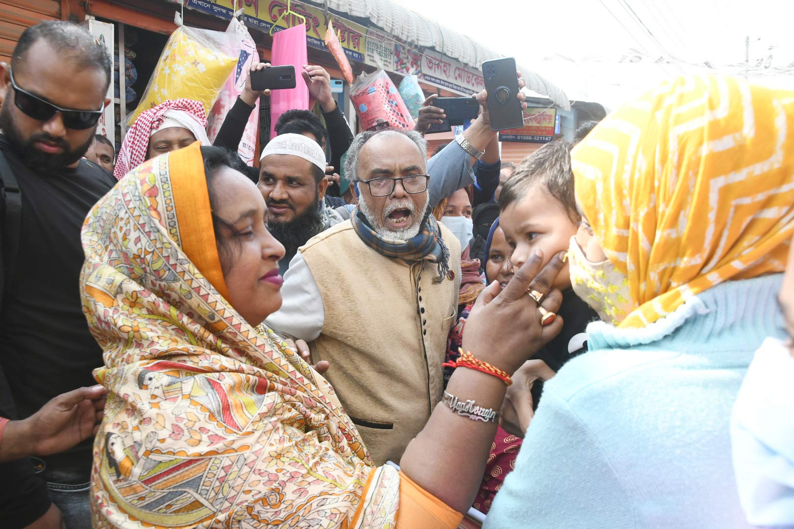 প্রচারণায় নেমে মায়ের কোলে থাকা এক শিশুর গাল টিপে আদর করছেন সেলিনা হায়াৎ আইভী।
