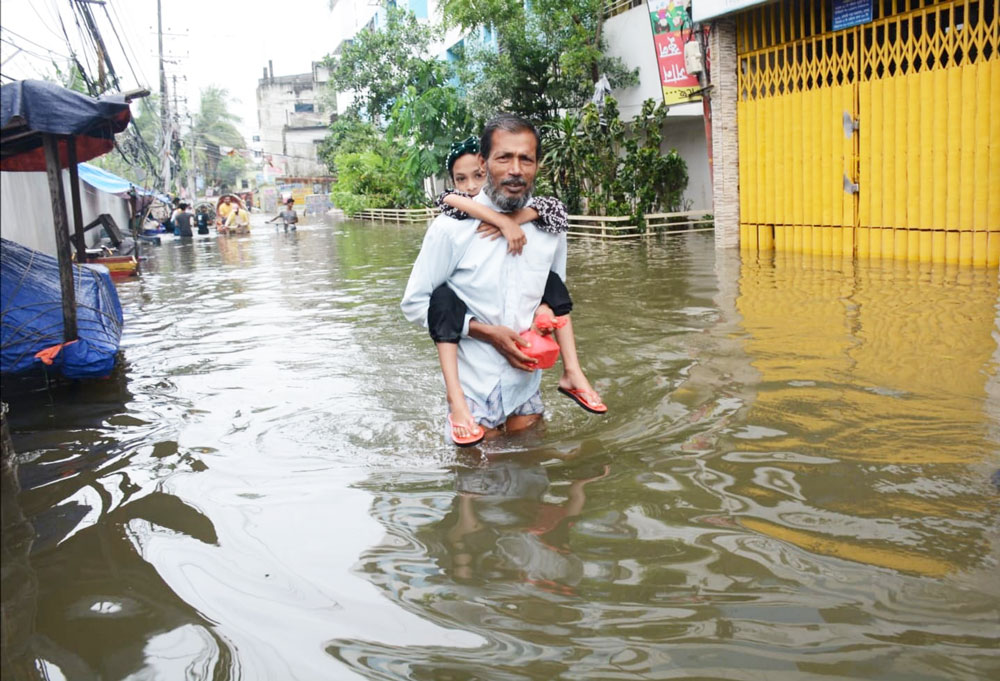 কয়েক দিনের টানা বৃষ্টি ও জোয়ারের কারণে কোমর সমান পানিতে যাতায়াত করতে হচ্ছে নগরবাসীকে। আজ চট্টগ্রাম নগরীর চকবাজার কাঁচা বাজার মোড় এলাকায়। ছবি: হেলাল সিকদার
