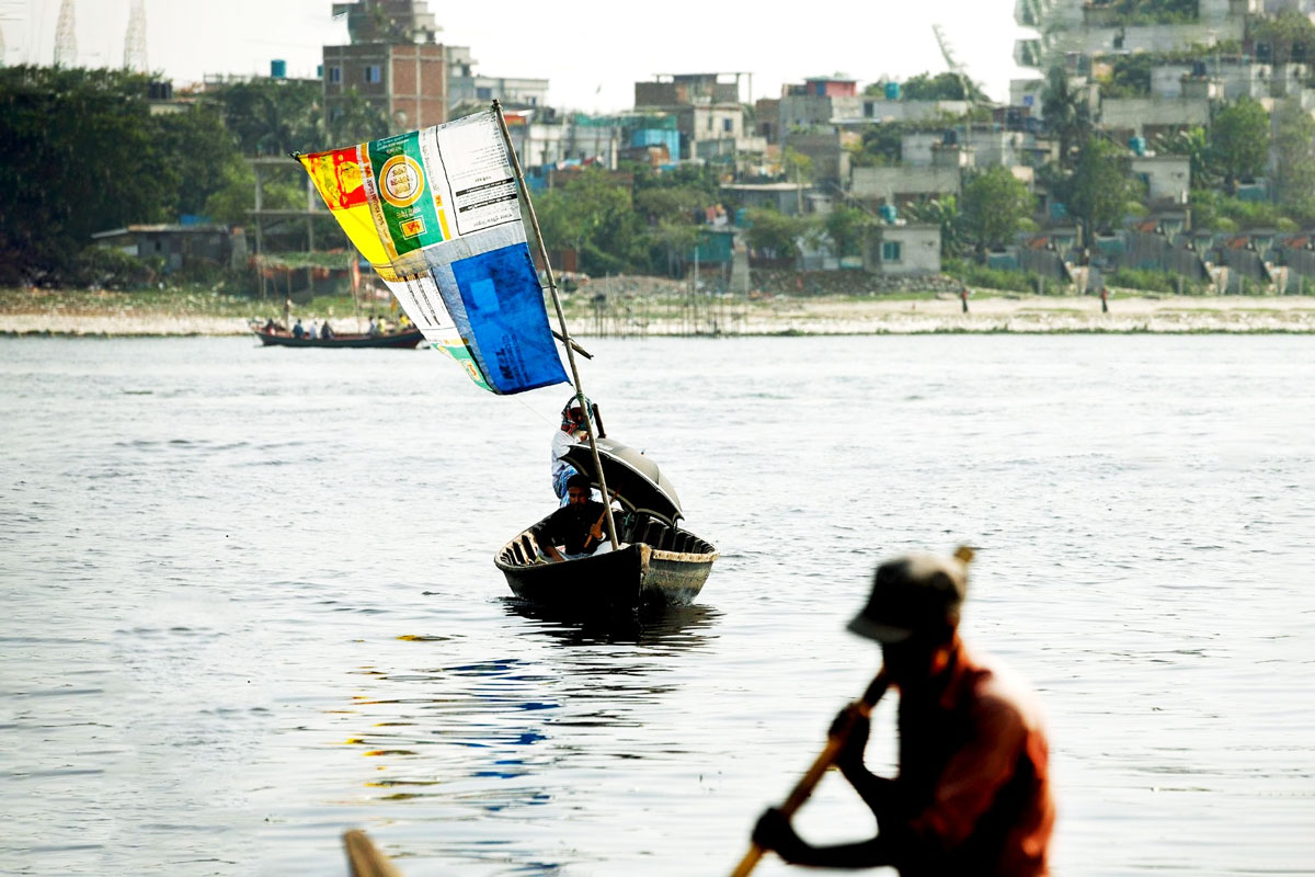 তীব্র নদীতে বইছে কিছুটা বাতাস। মাঝি তাঁর ছোট্ট ডিঙি নৌকায় পাল তুলে ভাসছেন নদীতে। বুড়িগঙ্গা নদী, শ্যামপুর, ঢাকা, ৭ জুন ২০২৩। ছবি: হাসান রাজা