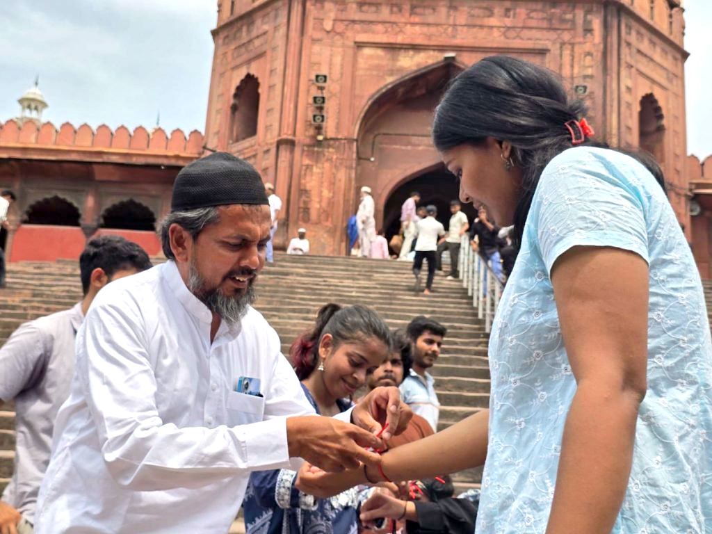 জামা মসজিদের সামনে একজন মুসলিম ব্যক্তি কেওয়াইএসের এক সদস্যের হাতে রাখি বেঁধে দিচ্ছেন। ছবি: সংগৃহীত
