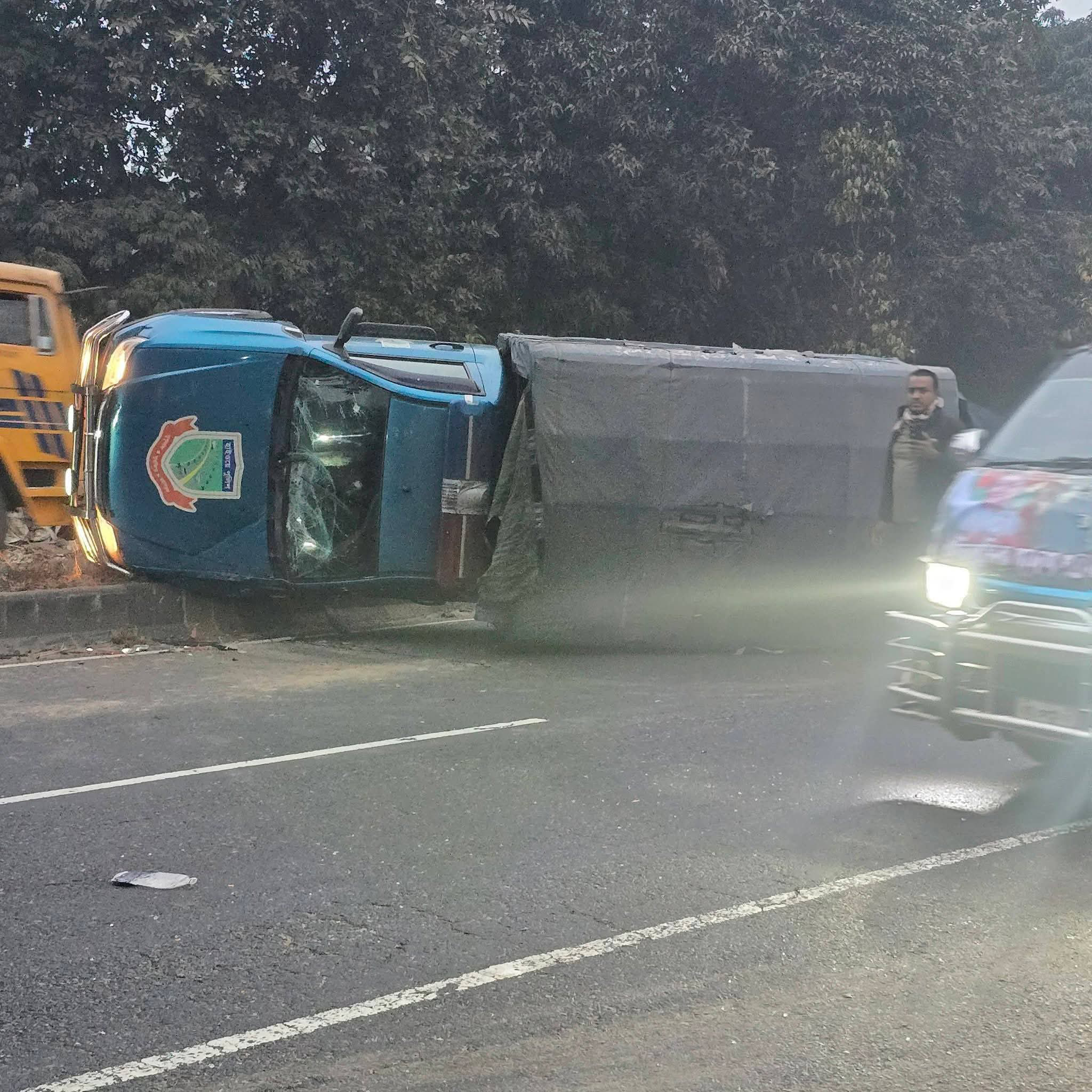 আজ ভোরে কাভার্ড ভ্যানের ধাক্কায় পুলিশের গাড়ি উল্টে যায়। ছবি: আজকের পত্রিকা