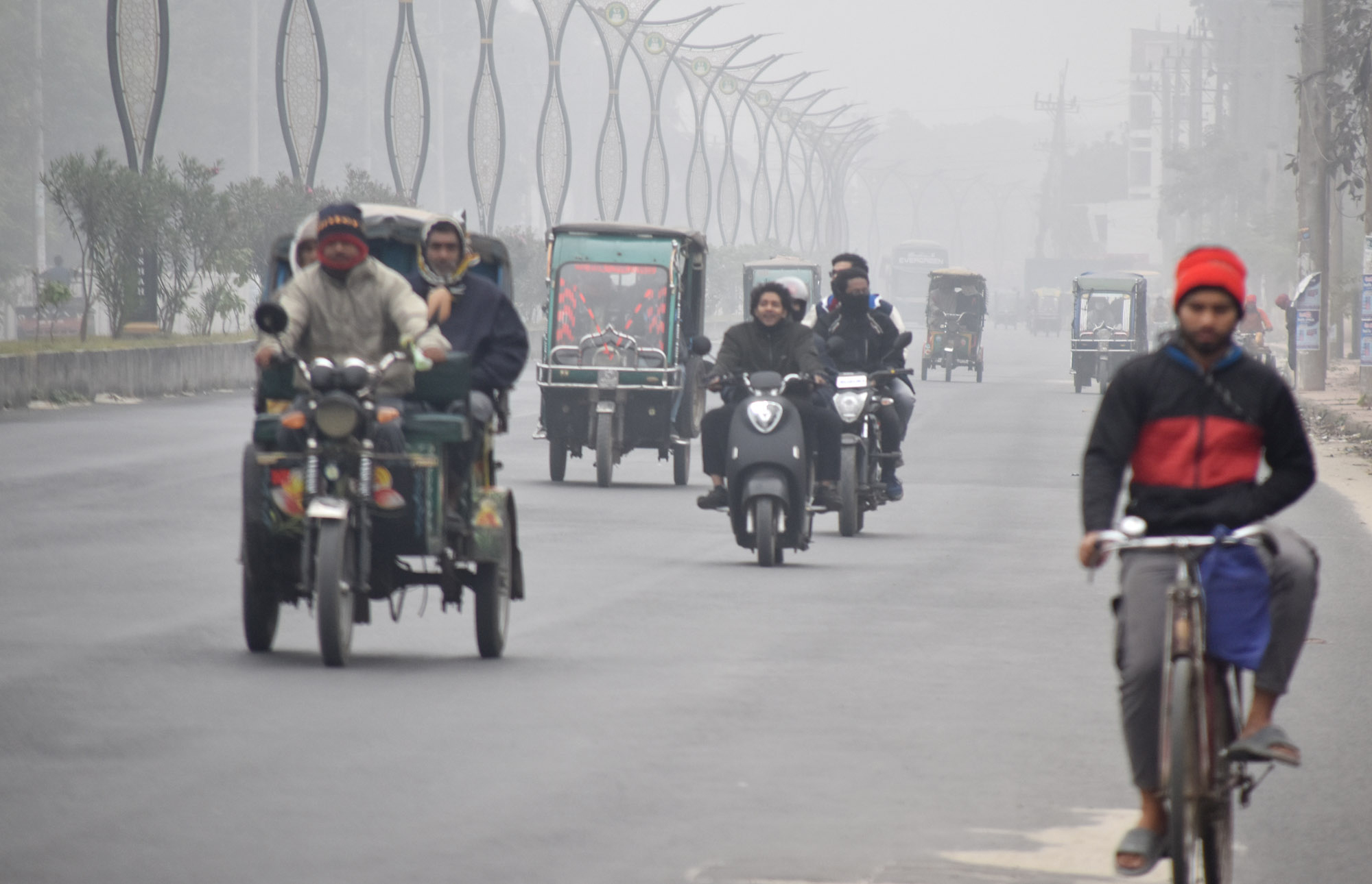 ঘন কুয়াশায় ঢাকা পড়েছে রাজশাহী শহর। শীতের মধ্যে গরম পোশাক পরে কাজে যেতে রাস্তায় বের হয়েছে লোকজন। কিছু যানবাহন সকালে হেডলাইট জ্বালিয়ে চলাচল করে। আজ সকাল সাড়ে ৯টায় বিনোদপুর এলাকা থেকে তোলা। ছবি: মিলন শেখ