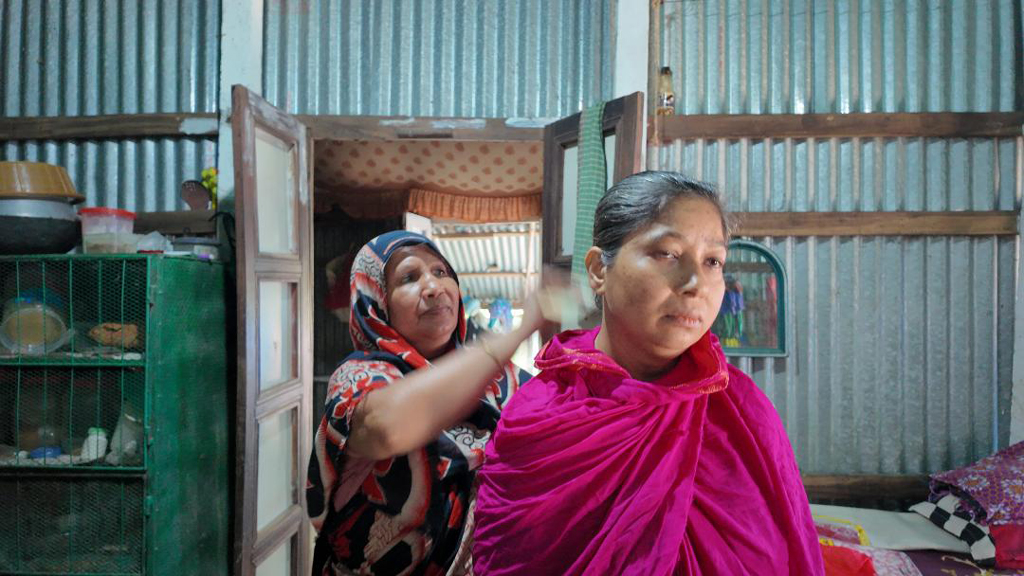 মেয়ের মাথায় তেল দিয়ে চিরুনি করে দিচ্ছেন। ছবি: আজকের পত্রিকা