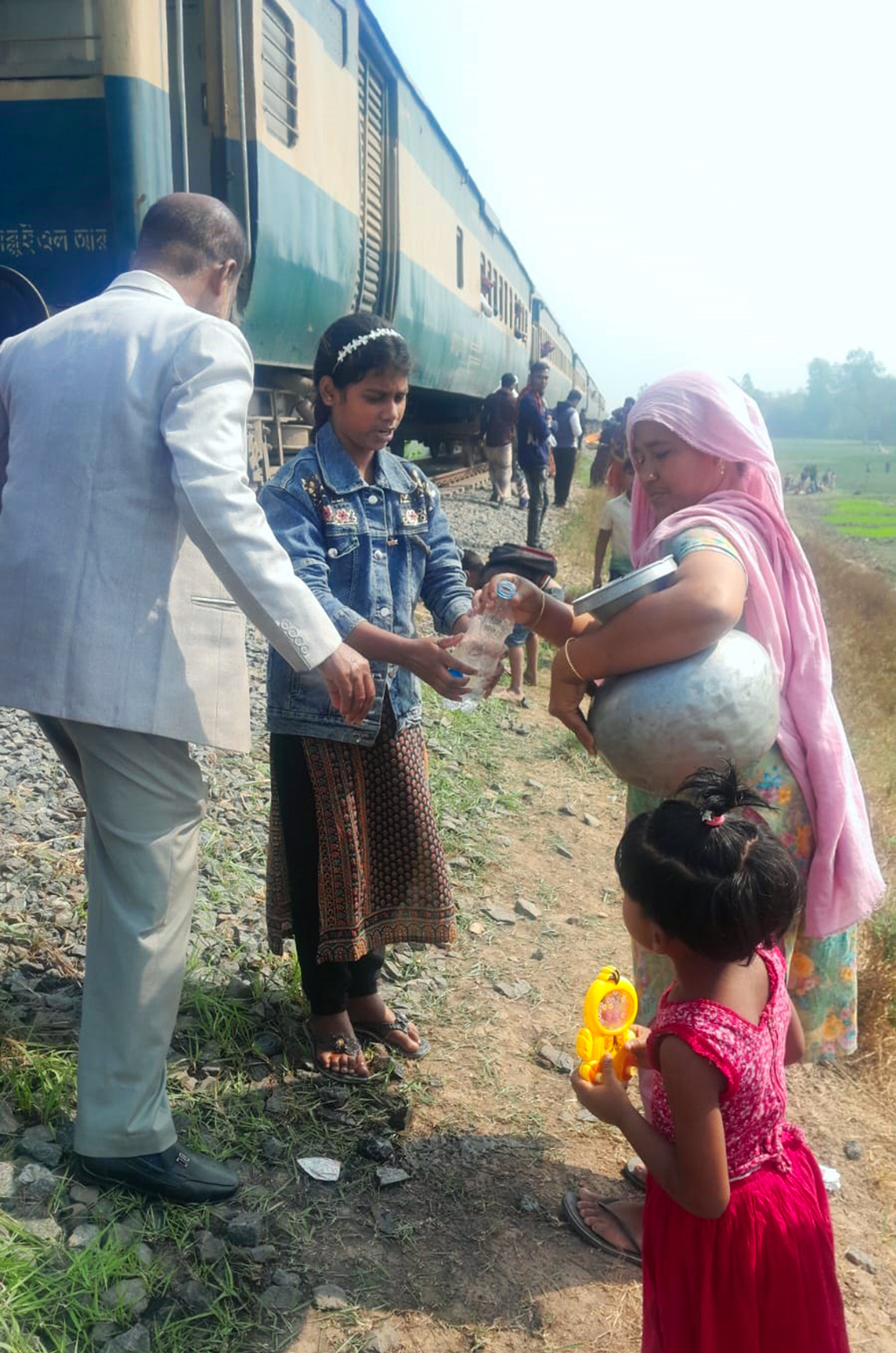 ট্রেনের ইঞ্জিন বিকল হওয়ায় ক্ষুধার্ত, তৃষ্ণার্ত মানুষের জন্য খাবার ও পানি নিয়ে এগিয়ে আসেন আশপাশের মানুষ। আজ রোববার বেলা ১১টার দিকে পাবনার সাঁথিয়া উপজেলার তাঁতীবন্দ এলাকায়। ছবি: সংগৃহীত