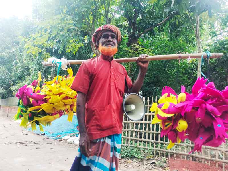 গ্রামে ঘুরে ঘুরে হ্যান্ডমাইক বাজিয়ে বাচ্চাদের খেলনা বিক্রি করেন তিনি। তুলো দিয়ে তৈরি রংবেরঙের মাছ, পাখিসহ বিভিন্ন খেলনাসামগ্রী মাথার চুল অথবা নগদ টাকার বিনিময়ে বিক্রি করেন। আজ সকালে রংপুরে গঙ্গাচড়া উপজেলার মেডিকেল পাড়া এলাকা থেকে তোলা। ছবি: আব্দুর রহিম পায়েল
