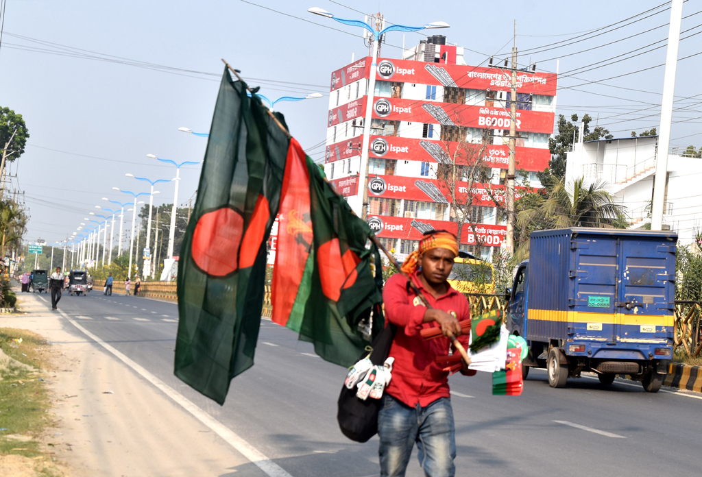 ১৬ ডিসেম্বর বিজয় দিবস উপলক্ষে বিভিন্ন এলাকায় ঘুরে ঘুরে জাতীয় পতাকা বিক্রি করছেন এক যুবক। রাজশাহী নগরীর আম চত্বর এলাকা থেকে তোলা ছবি। মিলন শেখ
