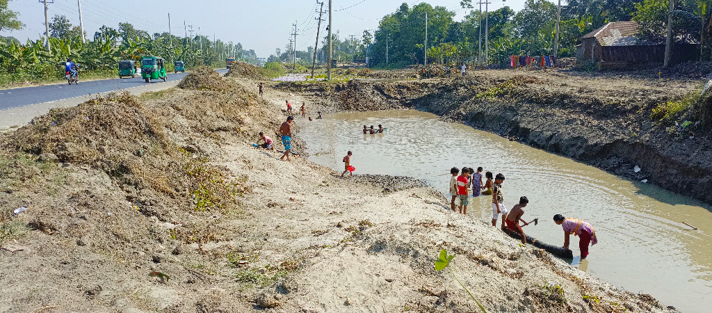 ঢাকা-সিলেট মহাসড়ক ছয় লেনে উন্নীত করার কাজে মাটি কেটে নেওয়ায় গর্তের সৃষ্টি হয়েছে। সেই গর্তে জমে থাকা পানিতে মাছ শিকার করছে শিশু-কিশোরেরা। রায়পুরা উপজেলার মাহমুদাবাদ নীলকুঠি কুকুরমারা এলাকা, নরসিংদী, ১৫ নভেম্বর ২০২৪। ছবি: হারুনূর রশিদ