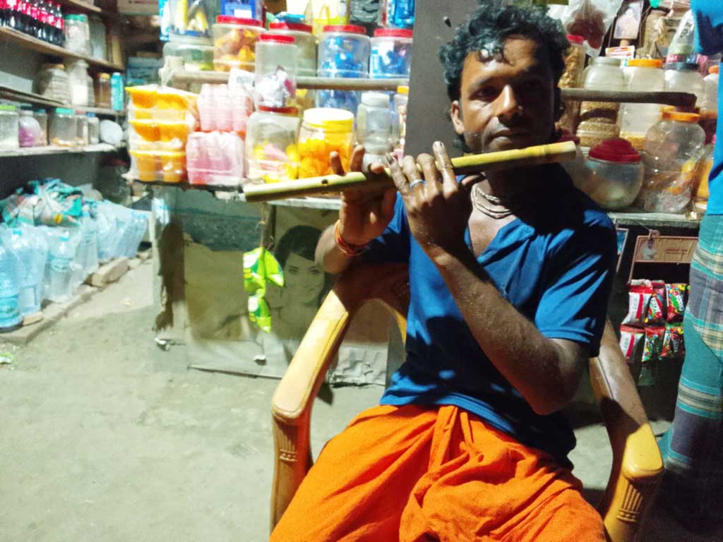 সন্ধ্যায় চায়ের দোকানে বাঁশি বাজাচ্ছেন সুব্রত শীল। ছবি: আজকের পত্রিকা