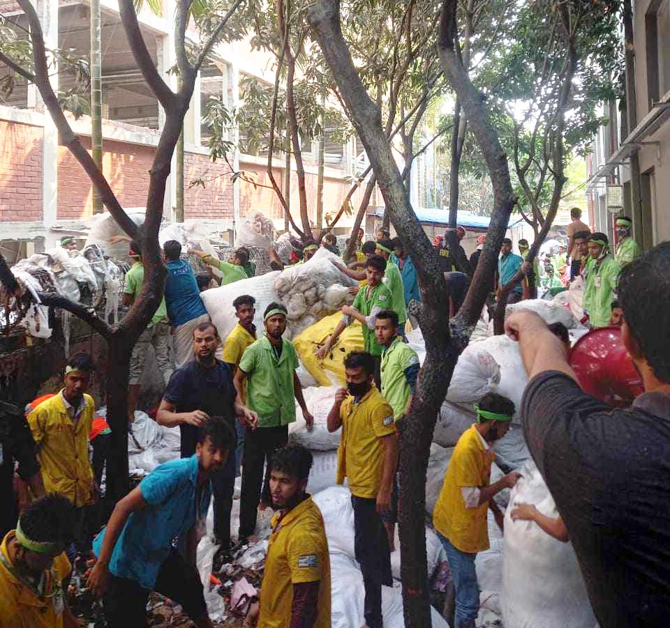 অগ্নিকাণ্ড থেকে রক্ষা করতে গুদামের ঝুট সরিয়ে নিচ্ছেন শ্রমিকেরা। আজ সোমবার নারায়ণগঞ্জের সিদ্ধিরগঞ্জে। ছবি: আজকের পত্রিকা