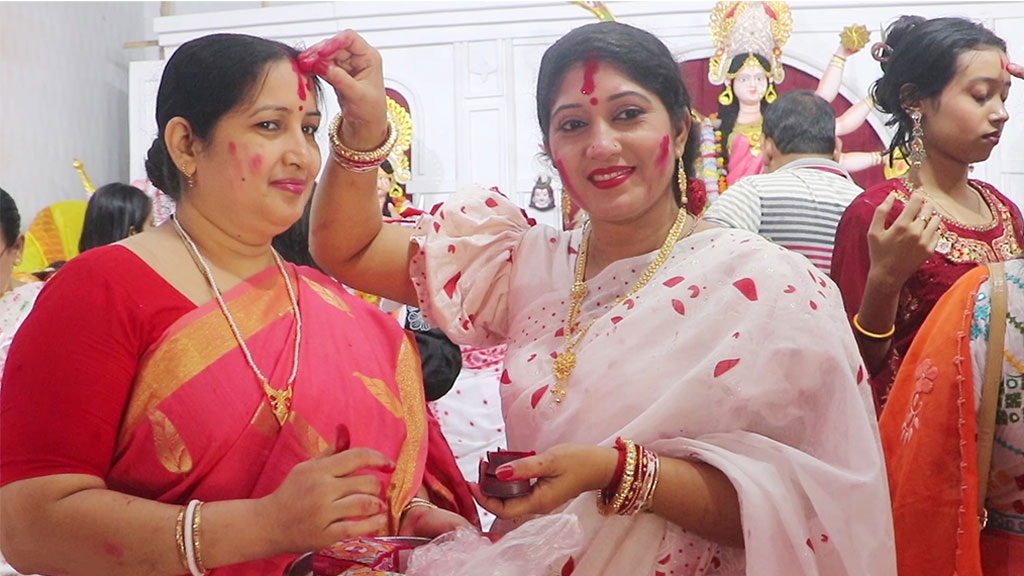 লাল-সাদা শাড়িতে সেজে দেবীবরণ ও সিঁদুর খেলায় মেতেছেন নারীরা। ছবি: আজকের পত্রিকা