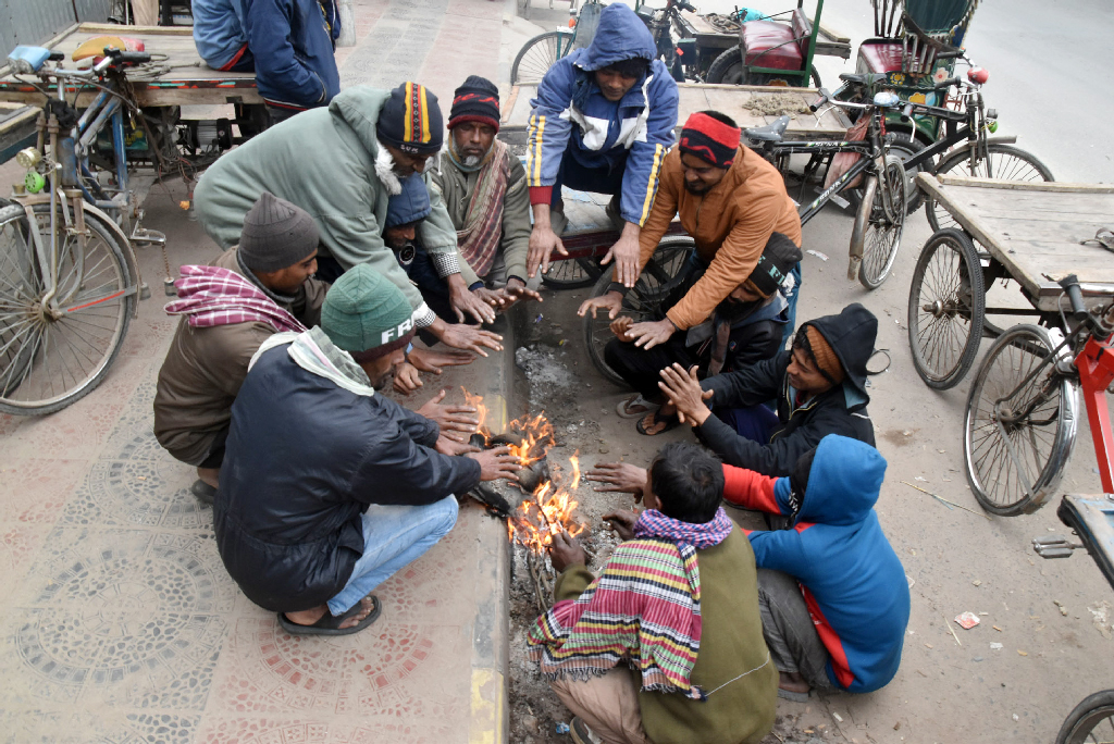 শীতের তীব্রতায় বিপর্যস্ত রাজশাহীর জনজীবন। দুপুর বেলায় কনকনে ঠান্ডায় রাস্তার পাশে আগুন জ্বালিয়ে তাপ পোহাচ্ছেন ভ্যানচালকেরা। নগরীর তেরখাদিয়া এলাকা থেকে তোলা। ছবি: মিলন শেখ