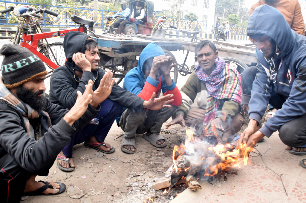 শীতের তীব্রতায় বিপর্যস্ত রাজশাহীর জনজীবন। দুপুর বেলায় কনকনে ঠান্ডায় রাস্তার পাশে আগুন জ্বালিয়ে তাপ পোহাচ্ছেন ভ্যানচালকেরা। নগরীর তেরখাদিয়া এলাকা থেকে তোলা। ছবি: মিলন শেখ